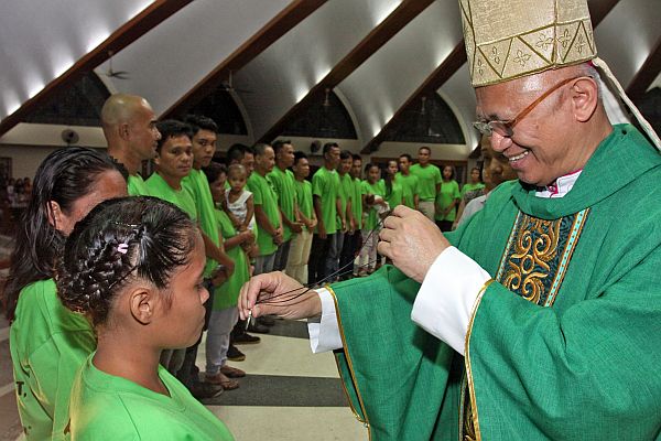 Cebu Archbishop Jose Palma congratulates with a big smile the first of the 25 drug surrenders who each received a medal and rosary from the prelate for completing their six-month barangay-based drug rehabilitation program, commemorated with a Mass that Palma officiated at the  San Roque Parish in Barangay Subangdaku, Mandaue City on Feb. 16, 2017. CDN PHOTO/JUNJIE MENDOZA