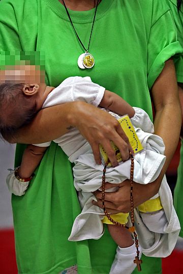 A BABY AND A ROSARY: This young woman, with her baby in her arms, still manages to hold on to the rosary she just received from Archbishop Jose  Palma, the prelate’s  graduation gift to those who finished their six-month barangay-based drug rehabilitation program.  CDN PHOTO/JUNJIE MENDOZA