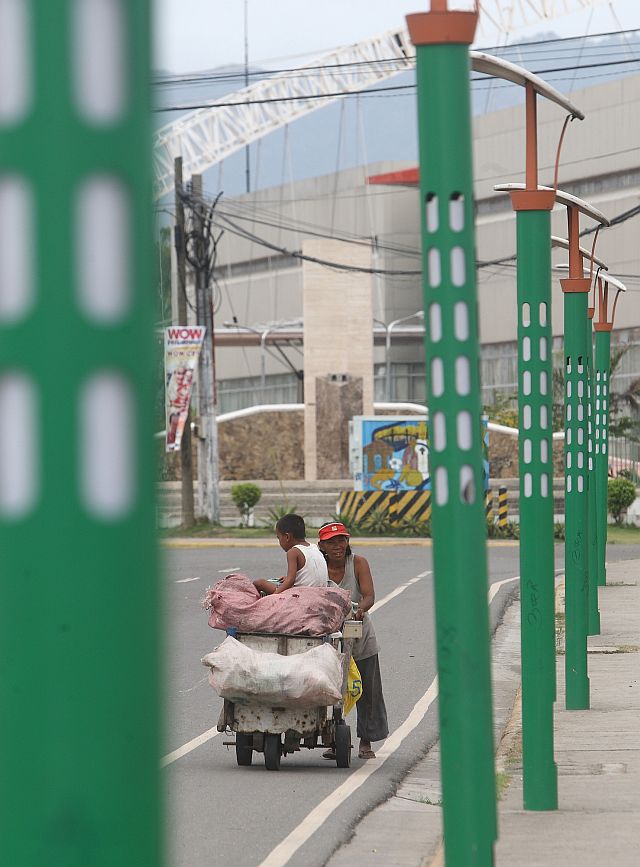  NOW GONE. Scavengers pass through a column of the controversial lampposts installed along the sidewalk of the streets in North Reclamation Area, Mandaue City in this photo taken on Feb. 4, 2009. The lampposts have since disappeared. (CDN FILE PHOTO)