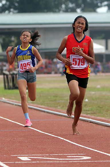 Barefoot runner Joan Alinsunod (right) of the City of Naga wins gold in the  secondary girls 1,500 meters on her birthday. Cebu City’s Mary Joy Loberanis bags silver.    (CDN PHOTO/TONEE DESPOJO)