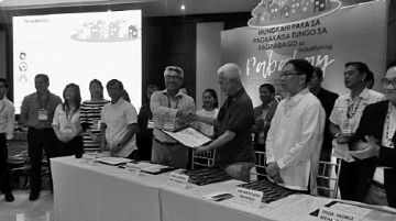 Christopher Narciso, Subdivision and Housing Developers Association president, (left) submits to Housing Secretary Leoncio Evasco Jr. a copy of the housing industry’s issues and the developers’ recommendations to the government during the national housing summit in Cebu City.  CDN photo/Victor Anthony V. Silva