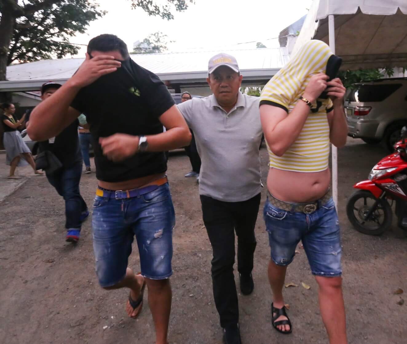 An NBI agent escorts two of the three Romanian Nationals who were the suspects in the Landbank ATM skimming at the NBI Head Quarter.(CDN PHOTO/JUNJIE MENDOZA)