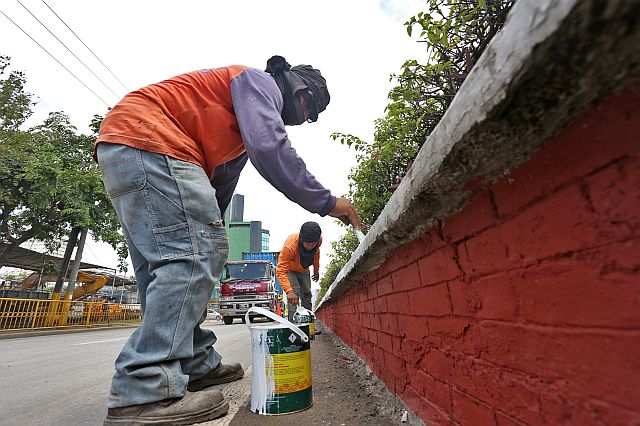 Workers of the Department of Public Works and Highways (DPWH-7) rush to repair and paint the center island and sidewalk along Pope John Paul II Ave. in Cebu City as part of preparations for the  Asean Summit meeting in Cebu next week. (CDN PHOTO/JUNJIE MENDOZA)