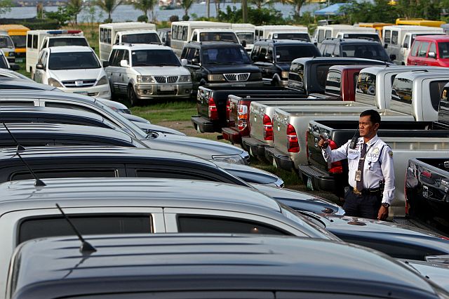 A security guard inspects city-owned vehicles impounded near Sugbo building at the South Road Properties after these were ordered recalled last year from the different barangays by then acting mayor Margot Osmeña.  CDN FILE PHOTO