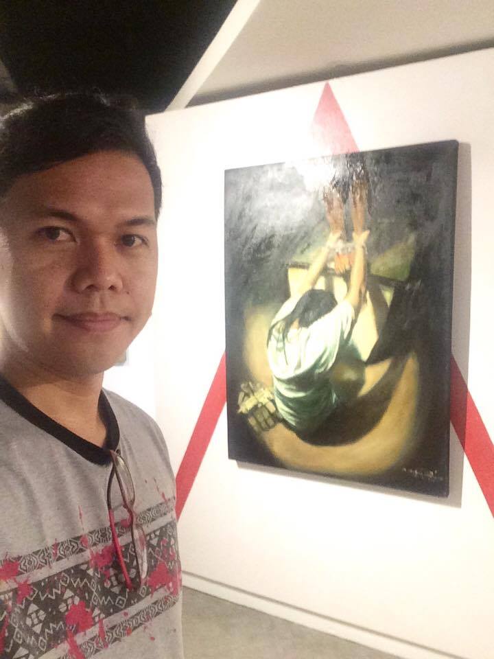 Fr. Leonard Realiza, OSA with one of his paintings on display at SM Art Center. (CONTRIBUTED)
