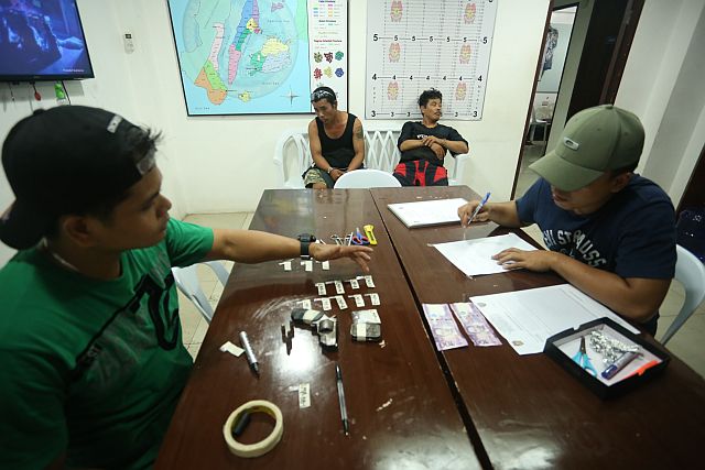 Operative of RAIDSOTG inventory the items they confiscated from two suspected drug pusher Jake Morales (left ) and Leo Paragas in a buy bust operation on Friday. (CDN PHOTO/LITO TECSON)