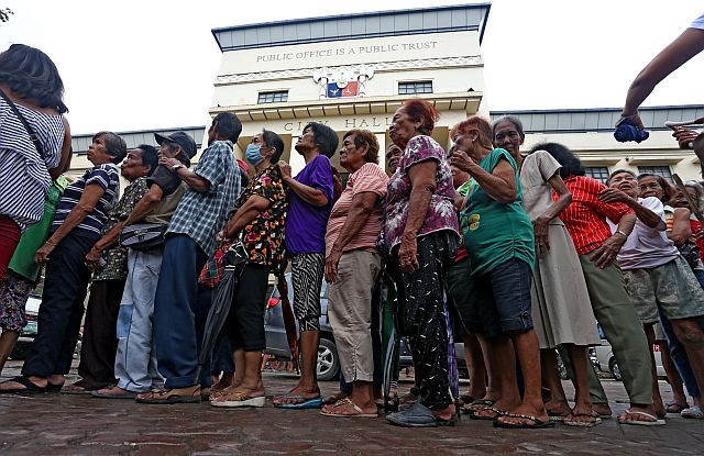 Cebu City’s indigent senior citizens line up to receive P1,500 from the Department of Social Welfare and Development (DSWD). Some of them sleep while others eat their meals to pass the long waiting time. (CDN PHOTO/JUNJIE MENDOZA)