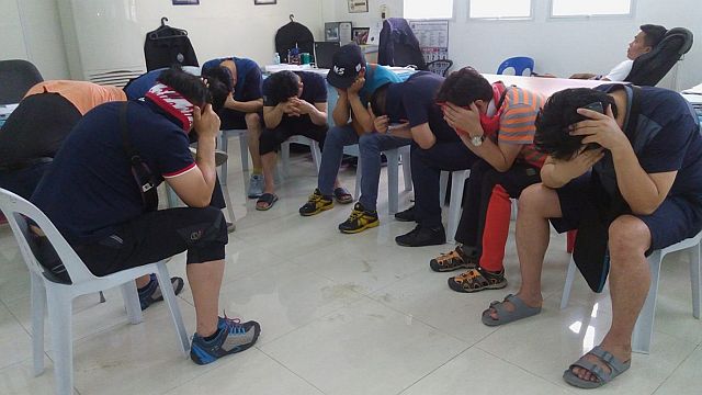 Nine Korean tourists who allegedly engaged the services of young women for sex cover their faces as they were presented to the media at the National Bureau of Investigation in Central Visayas office in Cebu City earlier this month. (CDN FILE PHOTO)