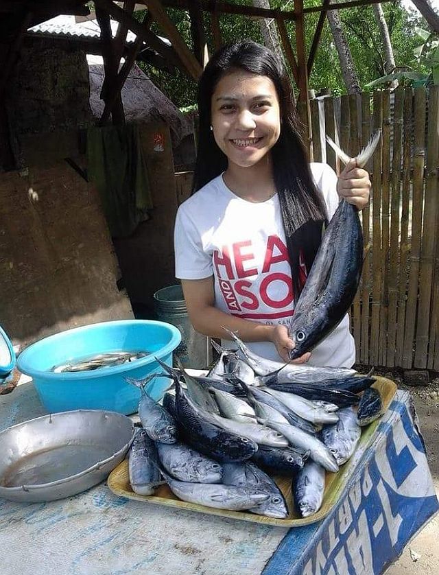 PROUD OF HER ROOTS. Regine Villamejor, proudly displays her father’s catch. She said she won’t forget how she achieved success by looking to her family’s sacrifice as her motivation to work harder for their future. (Contributed photo/USJ-R Intern Jheysel Ann S .Tangaro)