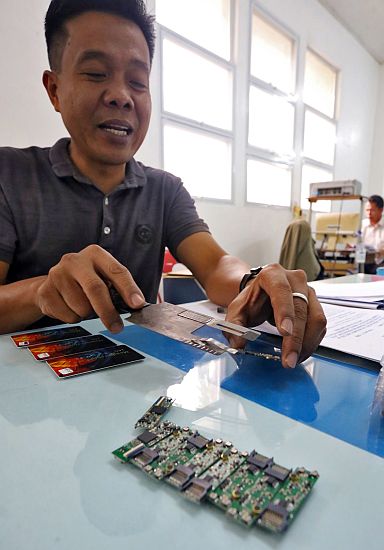 National Bureau of Investigation in Central Visayas (NBI-7) Special Investigator III Florante T. Gaoiran shows the ATM skimming gadgets confiscated from arrested Romanian nationals Ionut Alexandru Mitrache, Costel Ion and Razvan Aurelian Stancu in this photo taken at the NBI-7 office on March 18, 2017. (CDN PHOTO/JUNJIE MENDOZA)