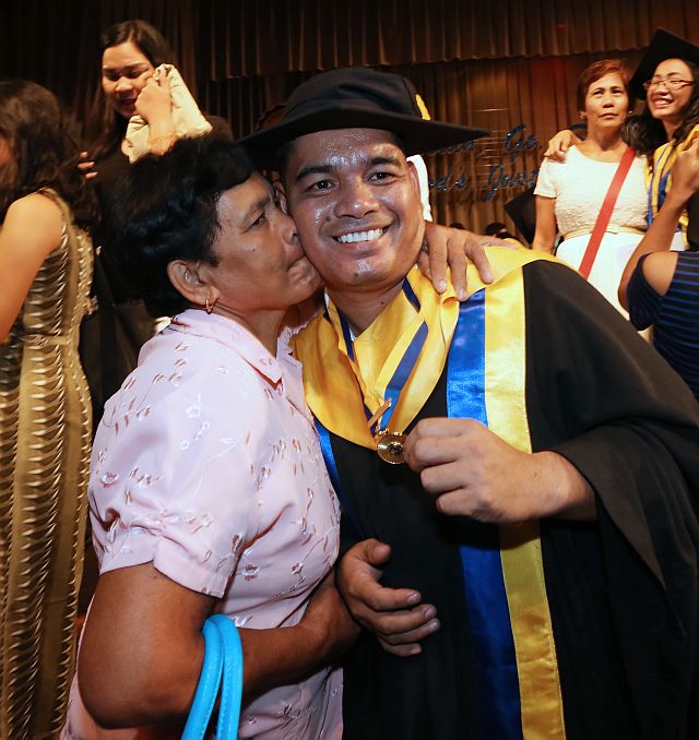  Saint Theresa’s College security guard Erwin Macua, who graduated cum laude with a Bachelor of Elementary Education degree, gets a kiss from his mother, Aproniana Macua. (CDN PHOTO/JUNJIE MENDOZA)