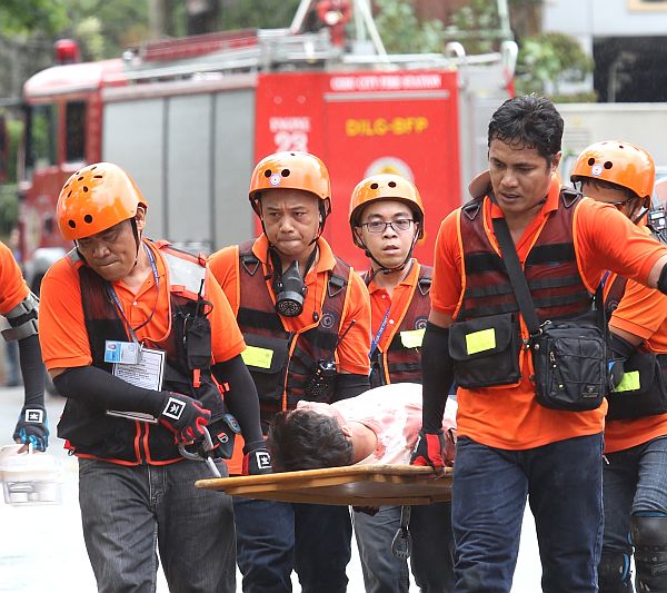 Rescue workers, simulating a collapsed building rescue, (above) carry an injured person during the earthquake drill at the Capitol compound.