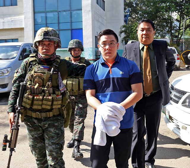 a heavily guarded Lim hides his handcuffs with a towel as he is brought to the Cebu City Prosecutor’s Office for inquest proceedings. (CDN PHOTO/JUNJIE MENDOZA)