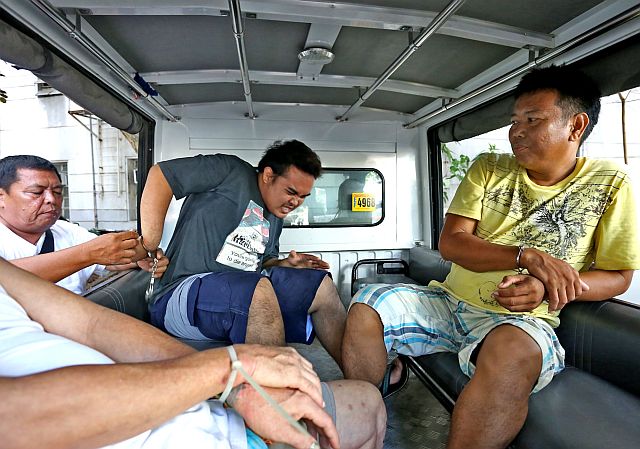 ENTRAPMENT. A policeman of the Consolacion Municipal Police Station (left) adjusts the handcuffs of Jeric Pepito (center) following his arrest on Tuesday, March 28, for selling illegal drugs while his uncle Giovanni Pepito (right, in yellow shirt) looks on. Giovanni also ends up in jail following his arrest on Wednesday night, March 29, for attempting to bribe the police in exchange for the filing of a lower crime case against his nephew. (CDN PHOTO/JUNJIE MENDOZA)
