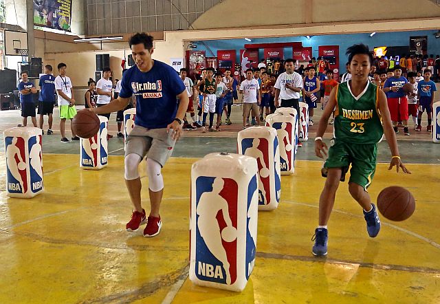 Dondon Hontiveros (left) shows the proper way of dribbling in yesterday’s Jr. NBA Philippines 2017 at the Don Bosco Technology Center. (CDN PHOTO/LITO TECSON)