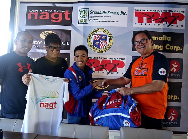 Rick Reyes (right), head coach of the Triathlon Association of the Philippines (TRAP) and Boying Rodriguez (2nd from left), Vice president of TRAP, turn over some training equipment to Cebuano triathlon national team member Kim Remolino. At left is Kim's father Andoy.  (CDN PHOTO/ LITO TECSON)