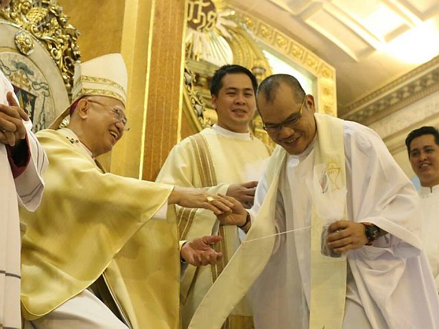 Fr. Roy Bucag (right) was welcomed with smiles and applause from Cebu Archbishop Jose Palma when he got the sacred oils during the Chrism Mass at the Cebu Metropolitan Cathedral. (CDN PHOTO/JUNJIE MENDOZA)