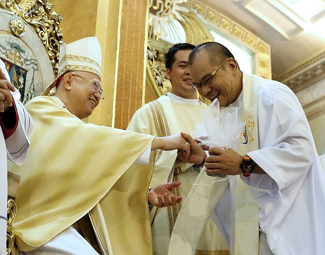  Fr. Roy Bucag, the fighting priest of Santa Fe, Bantayan Island,  smiles as he receives the sacred oil from Archbishop Jose Palma during the Chrism Mass at the Cebu Metropolitan Cathedral on Tuesday. (CDN PHOTO/JUNJIE MENDOZA)
