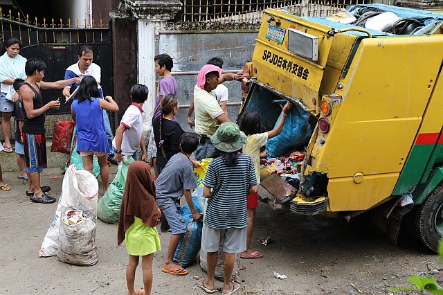  Residents from Cebu City’s interior sitios or zones  rush to load the bags of trash they collected into a compactor truck to be able to claim the cans of sardines the city is giving away in exchange for their garbage. (CDN PHOTO/TONEE DESPOJO)