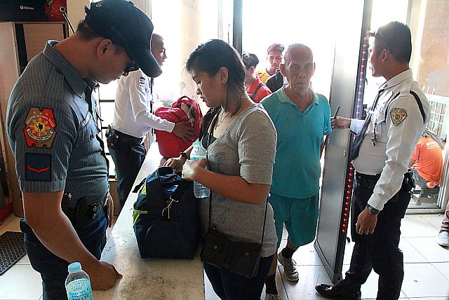 Police officers and security guards detailed at the Cebu South Bus Terminal (CSBT) inspect the bags of passengers entering CSBT amid the tightening of security at the terminal with the coming Holy Week when thousands of people are expected to travel for the long weekend.   CDN FILE PHOTO