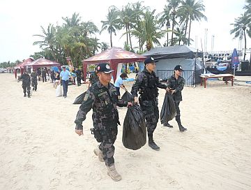 Police officers (left) from the Cebu Provincial Public Safety Company help clean the beach, a few hours after the Isla Music Festival 2017. Above, empty bottles are among those left by partygoers on the beach sand of Barangay Pooc in Santa Fe town.
