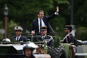 French President Emmanuel Macron (C) waves as he parades in a car on the Champs Elysees avenue after his formal inauguration ceremony on May 14, 2017 in Paris. /AFP 