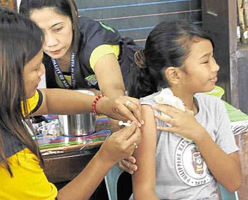 Health workers in Narvacan town in Ilocos Sur province gives a pupil vaccine to protect her from the human papilloma virus.  /Inquirer file photo