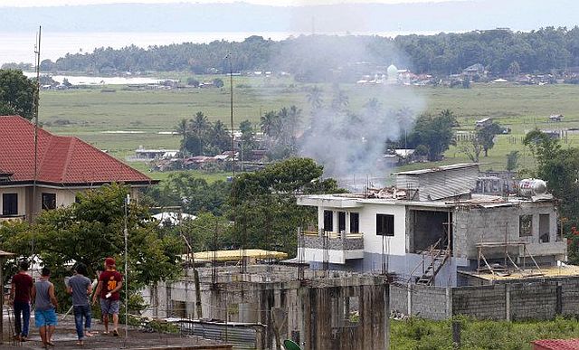  Residents watch a house that caught fire while government troops continue to battle with Muslim militants in Marawi City in southern Philippines, Thursday. /AP photo