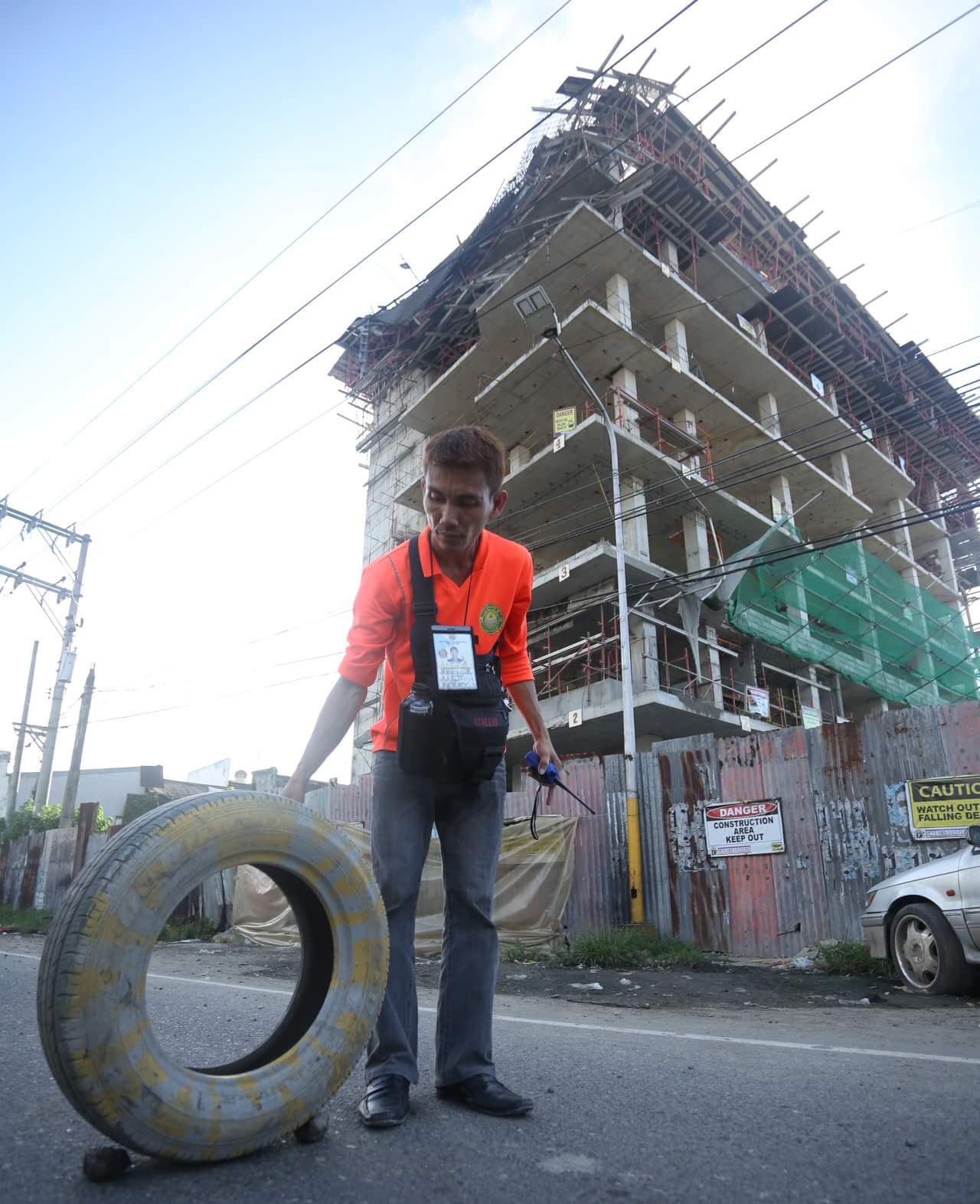 Librando Pulgo of Cebu City Rescue places a tire as a temporary early warning device after scaffoldings of a building being constructed along MJ Cuenco Ave. collapsed early morning Thursday. (LITO TECSON)