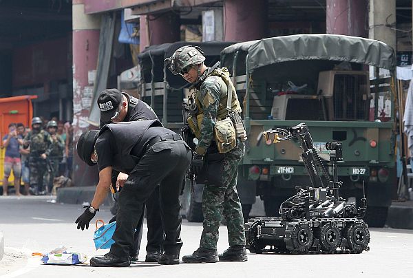Bomb squad members use an ICOR Calibre Mk3, a bomb detecting robot, to inspect a package that was left along the Quezon Bridge in Quiapo, Manila.  /Inquirer photo