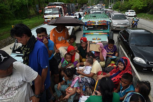 Resident fleeing from Marawi city,where gunmen who had declared allegiance to the Islamic State group rampaged through the southern city, are cramped on a truck as they traverse a traffic gridlock near a police checkpoint at the entrance of Iligan City, in southern island of Mindanao on May 24, 2017. Philippine President Rodrigo Duterte warned that martial law would be "harsh" and like a dictatorship, after imposing military rule in the south of the country to combat Islamist militants. / AFP PHOTO / TED ALJIBE