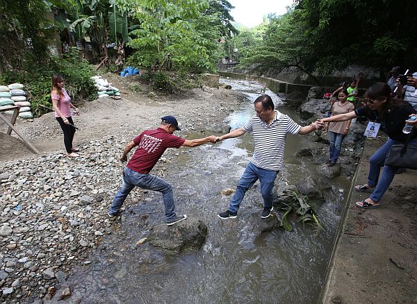Cebu City Councilor Joy Augustus Young crosses the river on his way to the Sapangdaku Elementary School for an inspection of ongoing rehabilitation works on the school building. .(CDN PHOTO/JUNJIE MENDOZA)