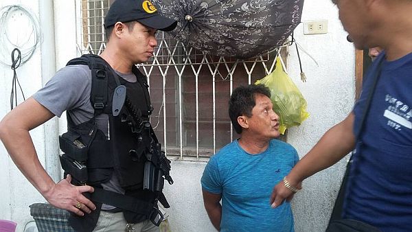Police operatives confront 55-year-old Danilo Ruiz outside his house after  packs of shabu, a gun and several ammunition were confiscated in a search.  Ruiz was reportedly the “middle man” of arrested Talisay City drug lord Steve Go. CDN PHOTO/BENJIE B. TALISIC)