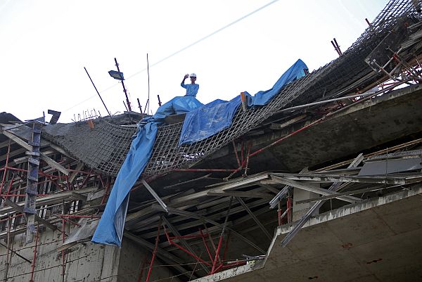 A worker waves from the seventh floor of the building project which gave way after its scaffoldings collapsed.  CDN Photo/Lito Tecson