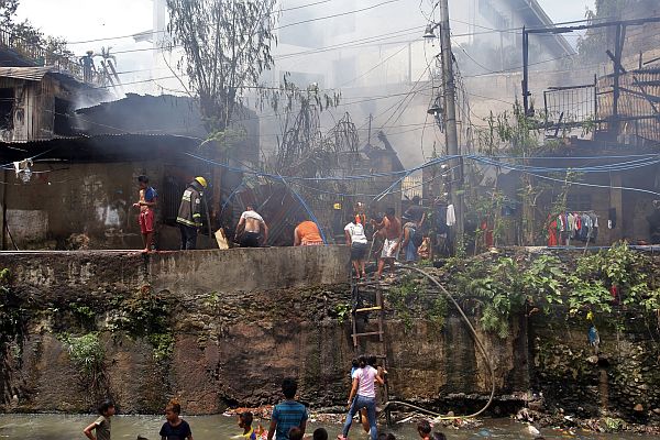 Residents try their best to put out the fire that eventually consumed their homes in Barangay Sambag 2.  CDN Photos/Junjie Mendoza