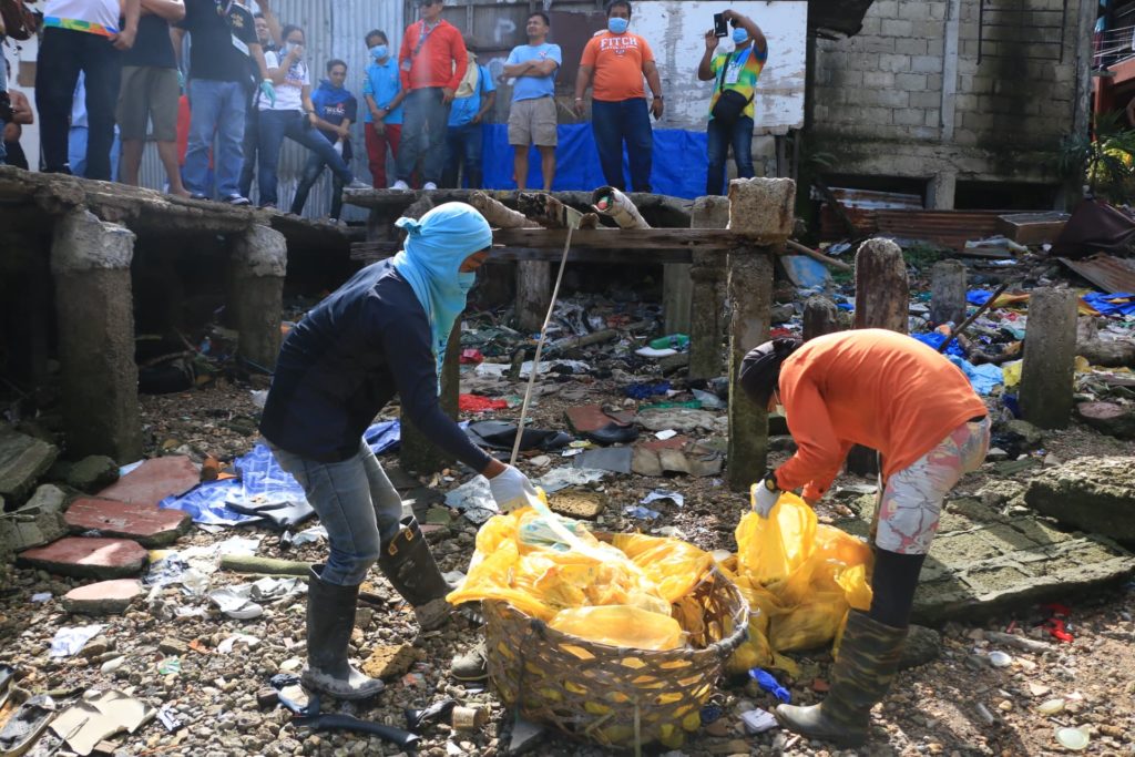 Individuals collecting personal waste in Lapu-Lapu city in front of bystanders