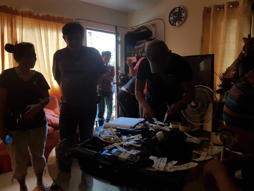 Cebu provincial police inventory the firearms and ammunition recovered from the house of confessed drug lord Franz Sabalones following an early morning search on Friday, March 1, 2019, in a unit he shared with his common-law wife Winefreda Misa  in Modena Subdivision of Barangay Tunghaan, Minglanilla, Cebu. Looking on is Minglanilla Mayor Elanito Peña (second to the right). |CDND Photo by Benjie Talisic