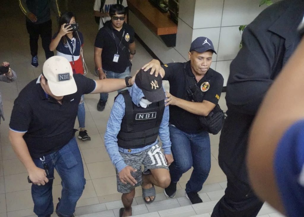 The 17-year-old suspect (center face covered with cloth) is escorted by NBI agents to the Lapu-Lapu City Prosecutor's Office on Monday, March 18, 2019, to face murder charges for the slaying of 16-year-old Christine Lee Silawan. 