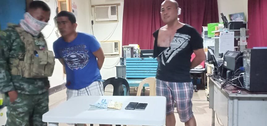 Jay-R dela Cruz (center) and Police Major Melvin Madrona, Criminal Investigation and Detection Group-Bacolod chief, are being processed at a Police Station in Bacolod City, Negros Occidental.|Photo courtesy of PNP-IMEG