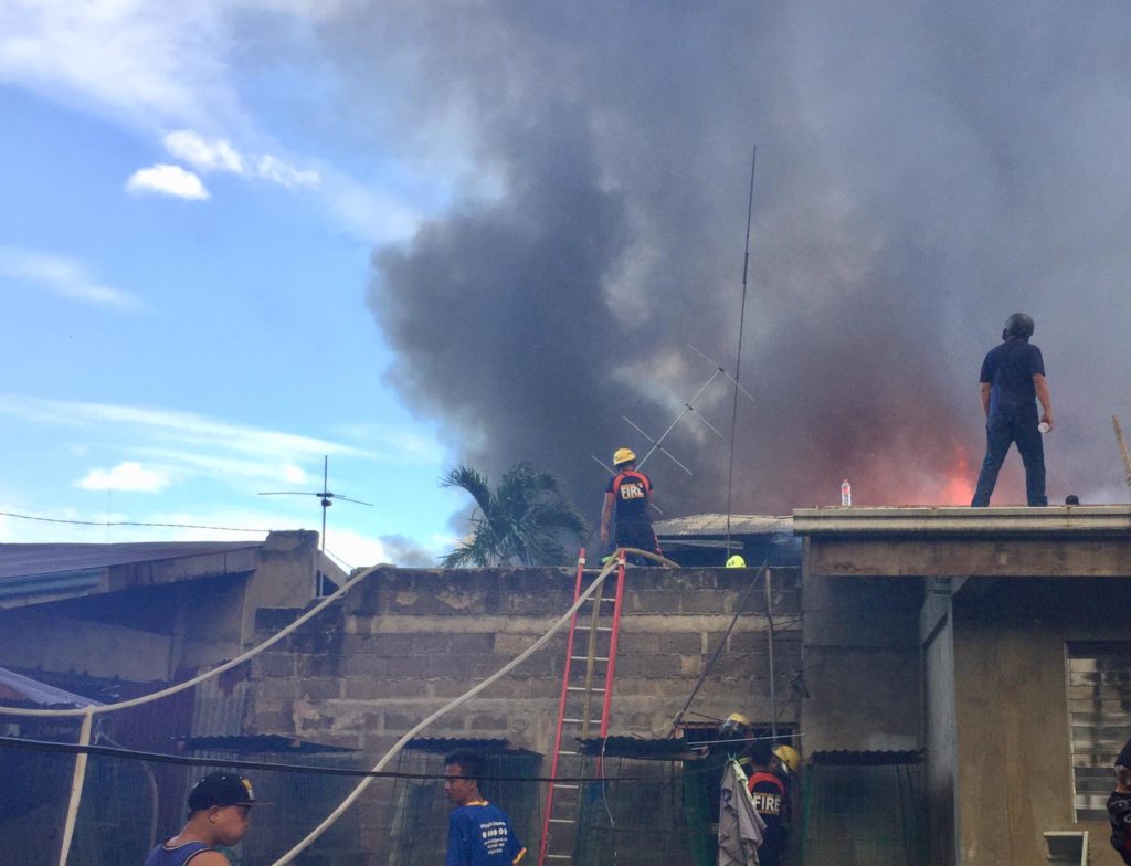 Firefighters climb the roof of one of the houses as they battle the fire in Sitios Bayabas and Ternate in Barangay Ibabao-Estancia, Mandaue City at past noon of February 29, 2020.