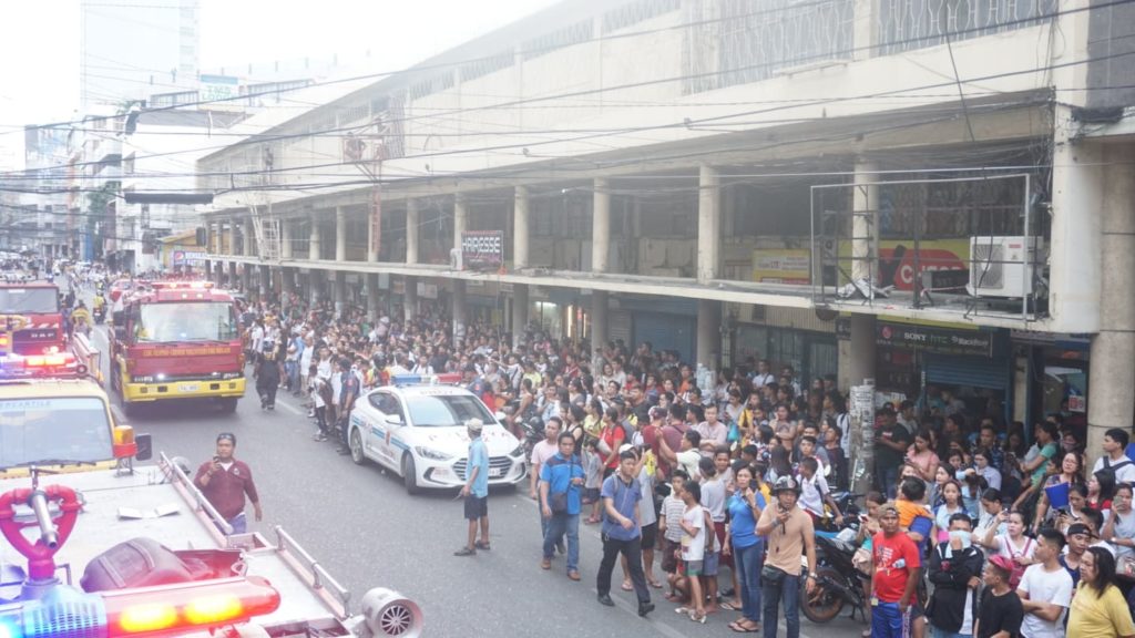 Bystanders occupy one side of the road in downtown Cebu City as they watch firefighters battle a fire of a fastfood store inside mall. | Gerard Francisco