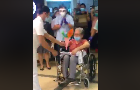 A health worker from VSMMC gives Mommy Elizabeth a bouquet of paper Origami flowers as the elder was discharged on April 24, 2020. Mommy Elizabeth is VSMMC's first patient who recovered from COVID-19 | Screenshot from VSMMC's Live Facebook Video