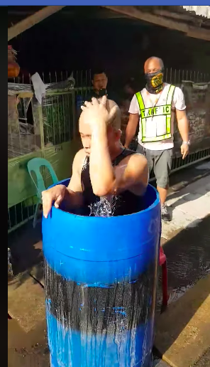 A volunteer of Sitio Baca, Barangay Apas, Cebu City, plays a resident refusing to be sprayed with disinfectants, jumps into a barrel full of water in this hilarious video. | Screen grab from Borden video
