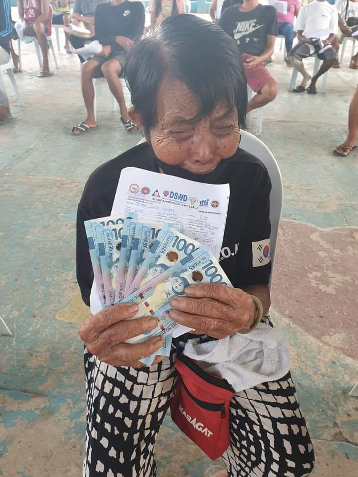 Nanay Celsa, an elderly woman from Dumanjug town, sheds tears of joy after receiving her much-awaited cash aids from the government in Barangay Ilaya, Dumanjug, Cebu, last April 30, 2020. | Contributed photo from: Snow Agravante