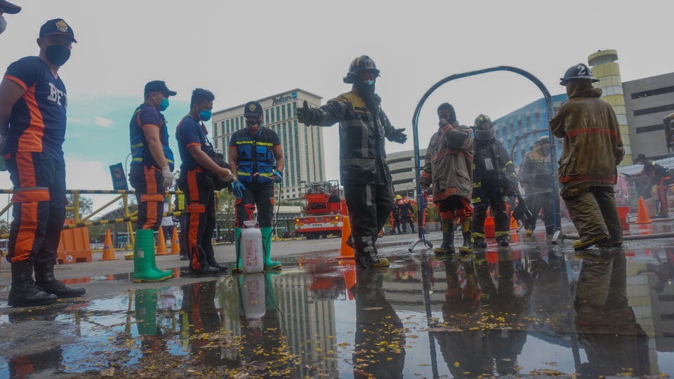 Firefighters undergo the disinfection process, a measure to prevent COVID-19 infection, after they put out a parking lot fire at the SM City Cebu mall. | Gerard Francisco