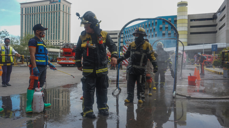 Firefighters undergo the disinfection process after they put out a fire at the fifth floor parking lot of SM City Cebu at past 2 p.m. on Friday, May 15, 2020. | Gerard Francisco