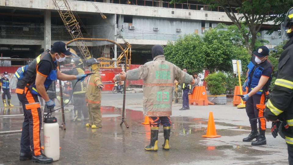 A firefighter undergoes the disinfection process after the firefighters put out the parking lot fire at SM City Cebu mall on Friday, May 15. | Gerard Francisco