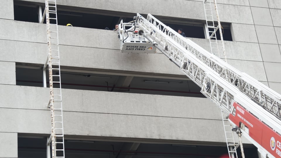 Firefighters use an aerial ladder to reach the fifth floor parking lot of SM City Cebu which has been damaged by the fire. | Gerard Francisco