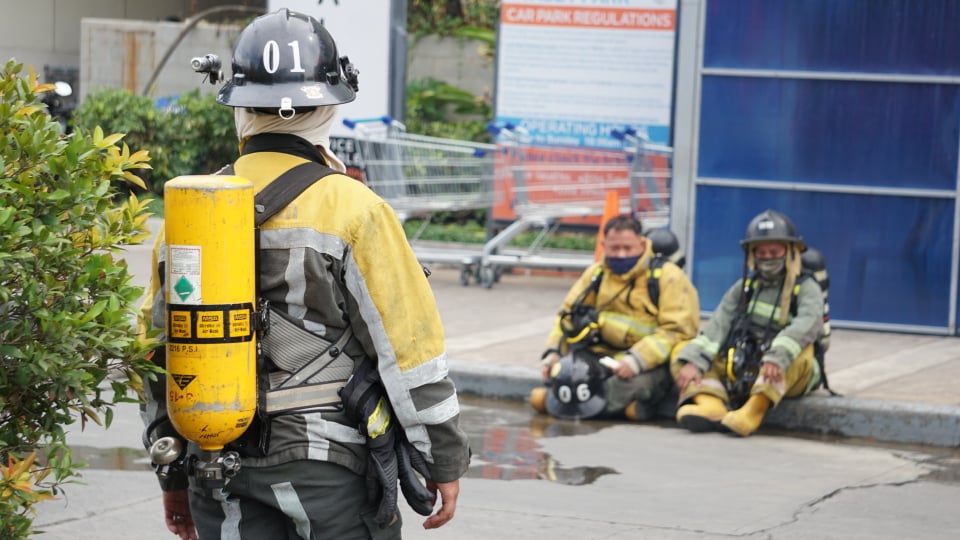 Exhausted firefighters take a break at the sidewalk after they put out the fire at the fifth floor parking lot of SM City Cebu. | Gerard Francisco