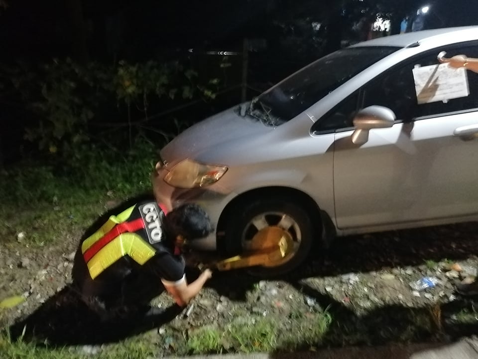 CCTO OPERATION. A member of the Cebu City Transportation Office or CCTO clamps an illegally parked vehicle in Cebu City. |Photo courtesy of Cebu City Transportation Office